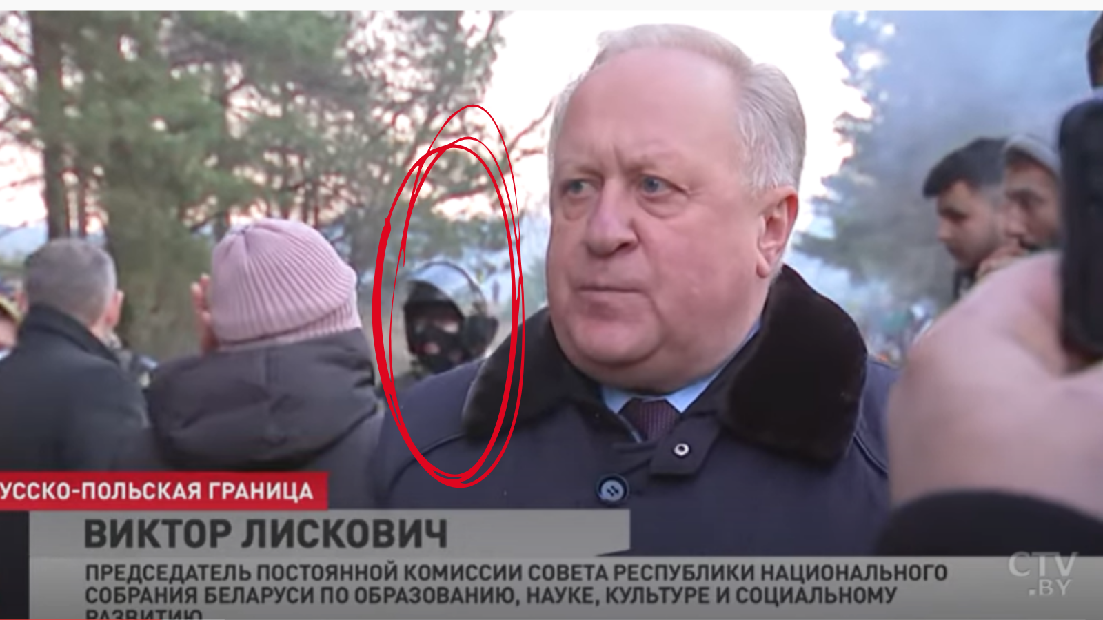 Armed Belarusian guards visible behind a parliamentarian during a TV interview